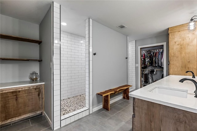 full bath featuring visible vents, a sink, a walk in shower, a walk in closet, and tile patterned floors