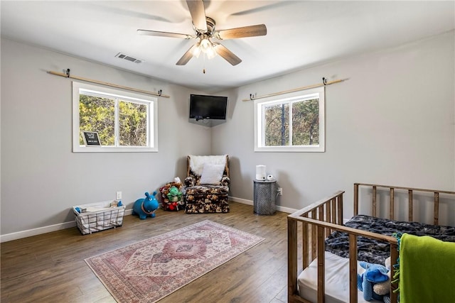 bedroom featuring hardwood / wood-style floors, baseboards, visible vents, and a ceiling fan