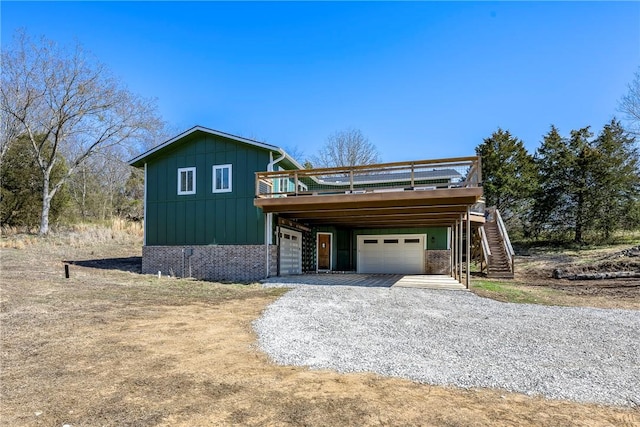 view of front facade with a deck, gravel driveway, board and batten siding, a garage, and stairs