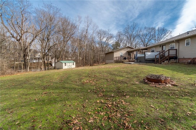 view of yard featuring a wooden deck, an outbuilding, an outdoor fire pit, and a shed