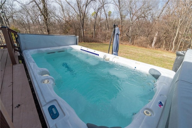 view of pool with a lawn and a hot tub