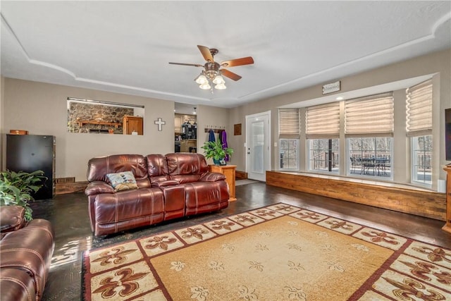 living area with finished concrete flooring, baseboards, and ceiling fan