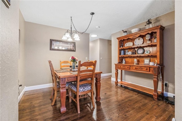 dining room with a textured wall, an inviting chandelier, baseboards, and wood finished floors