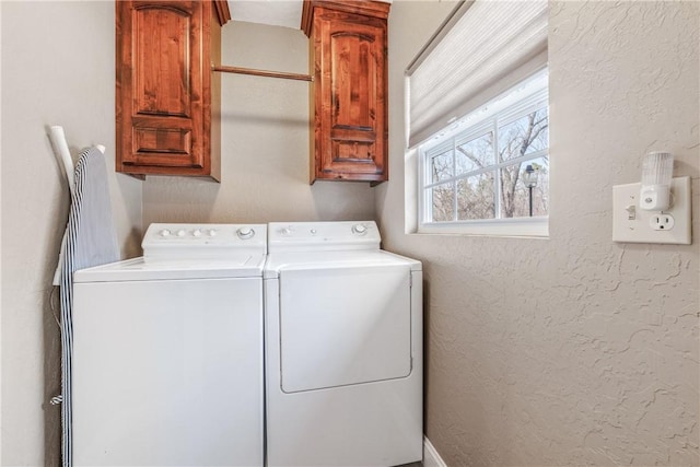 laundry area featuring cabinet space, a textured wall, and washer and clothes dryer