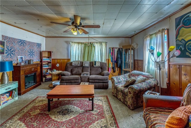 carpeted living room with a glass covered fireplace, crown molding, a wainscoted wall, and a wealth of natural light