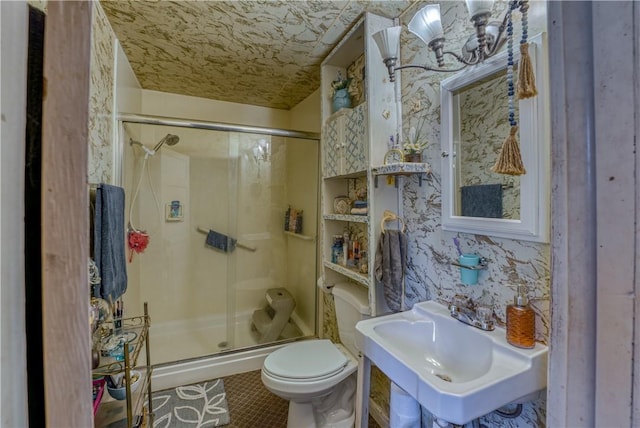 bathroom featuring wallpapered walls, toilet, a stall shower, tile patterned floors, and a sink