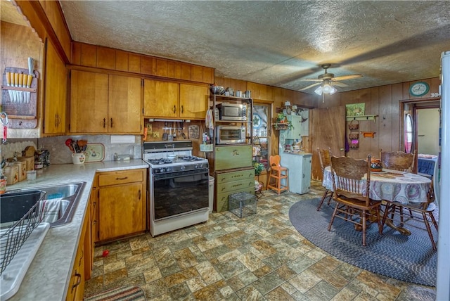 kitchen with range with gas cooktop, light countertops, stainless steel microwave, and brown cabinets