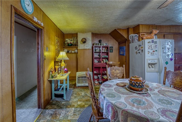 dining room with stone finish flooring, heating unit, wood walls, and a textured ceiling