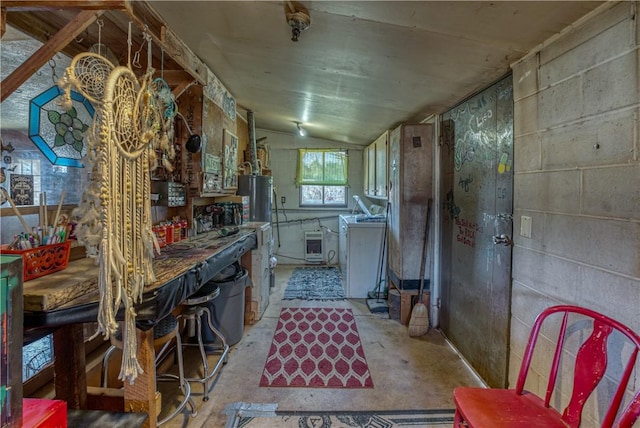 kitchen with water heater, unfinished concrete floors, washer / clothes dryer, and vaulted ceiling