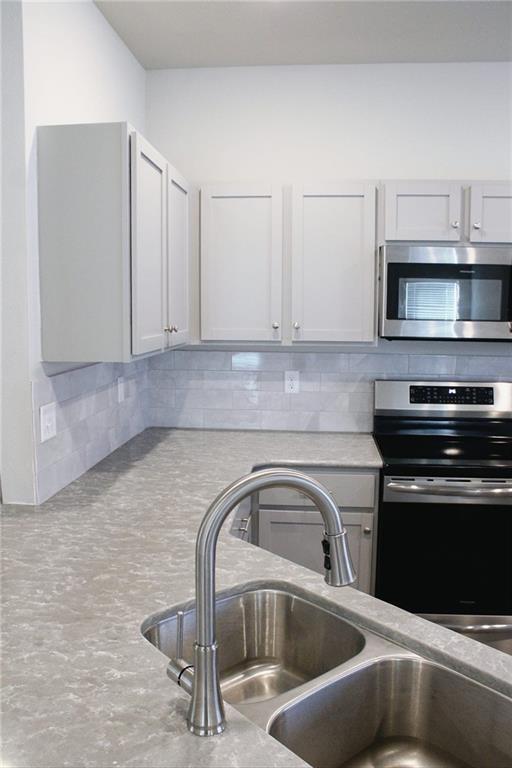 kitchen featuring a sink, light countertops, backsplash, and stainless steel appliances