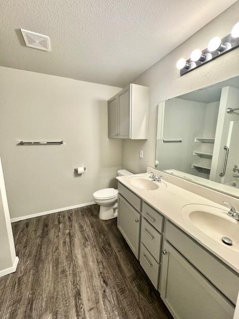 full bathroom with visible vents, a textured ceiling, wood finished floors, and a sink