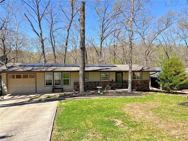 view of front facade with solar panels, concrete driveway, a front yard, stone siding, and an attached garage