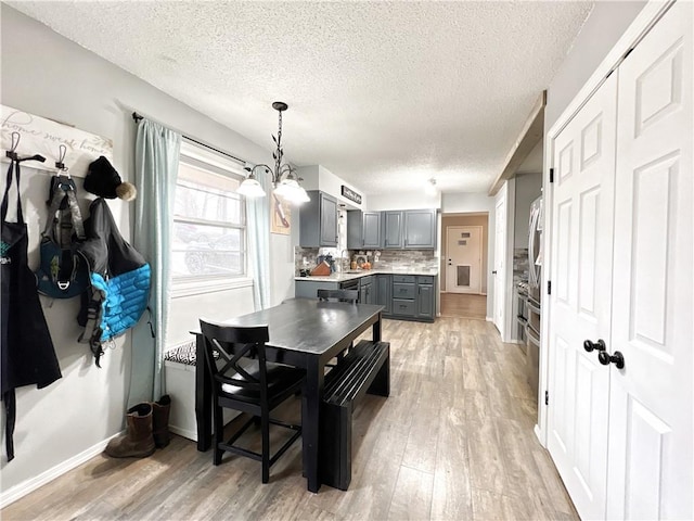 dining area with light wood-style flooring, baseboards, and a textured ceiling