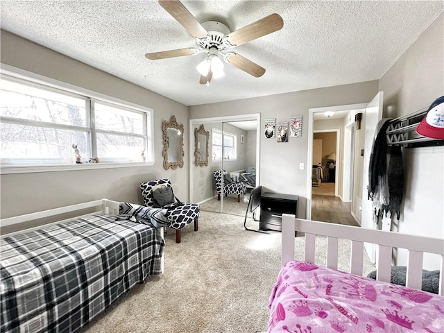 carpeted bedroom with ceiling fan, baseboards, a closet, and a textured ceiling