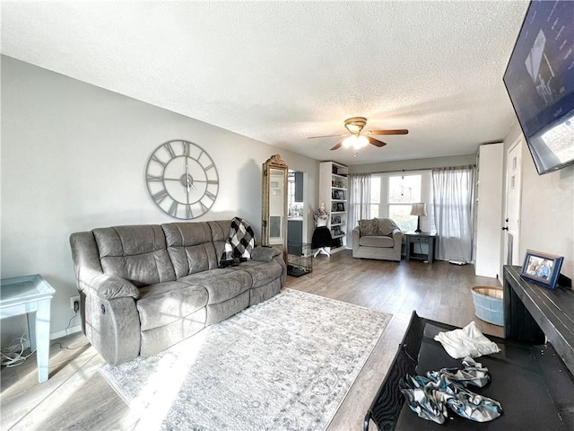 living area featuring ceiling fan, baseboards, a textured ceiling, and wood finished floors