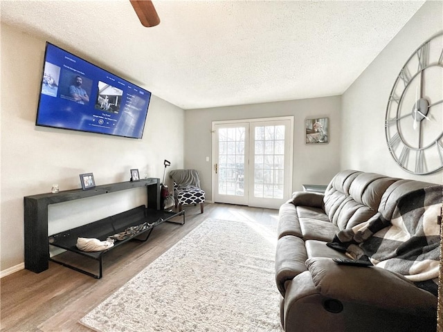 living room featuring a textured ceiling, baseboards, and wood finished floors