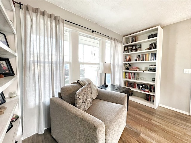 sitting room featuring a textured ceiling, baseboards, and wood finished floors