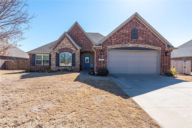 view of front facade with brick siding, fence, concrete driveway, stone siding, and an attached garage