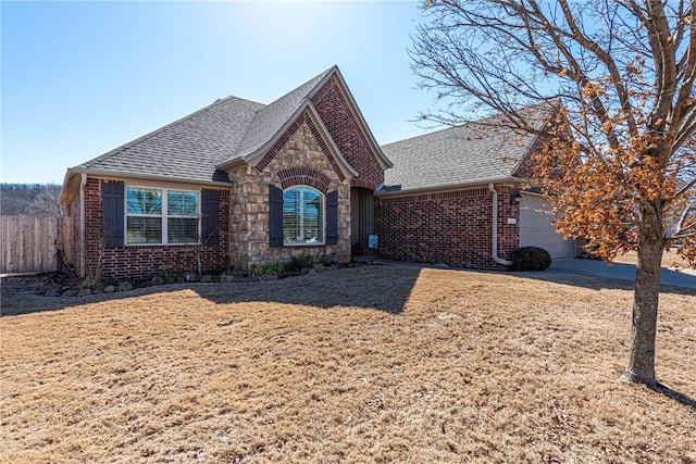 view of front of house with brick siding, a shingled roof, fence, a garage, and stone siding