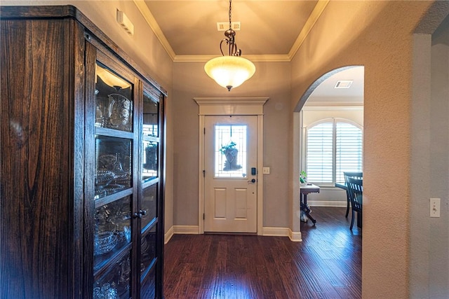 foyer featuring visible vents, crown molding, baseboards, dark wood-type flooring, and arched walkways