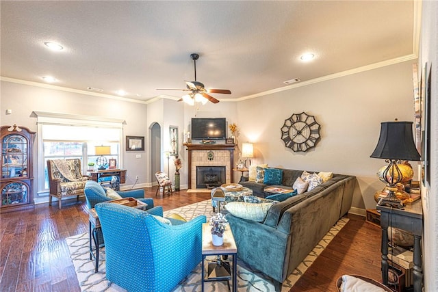 living room featuring visible vents, a tiled fireplace, hardwood / wood-style floors, arched walkways, and baseboards