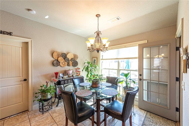 dining room with light tile patterned flooring, visible vents, and an inviting chandelier