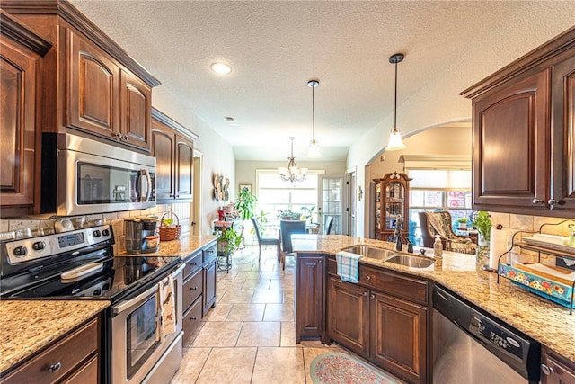 kitchen featuring a sink, light stone counters, tasteful backsplash, stainless steel appliances, and a peninsula