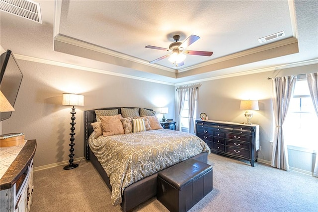 carpeted bedroom featuring visible vents, multiple windows, and a raised ceiling