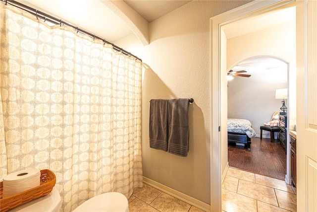 bathroom featuring connected bathroom, baseboards, ceiling fan, toilet, and tile patterned floors