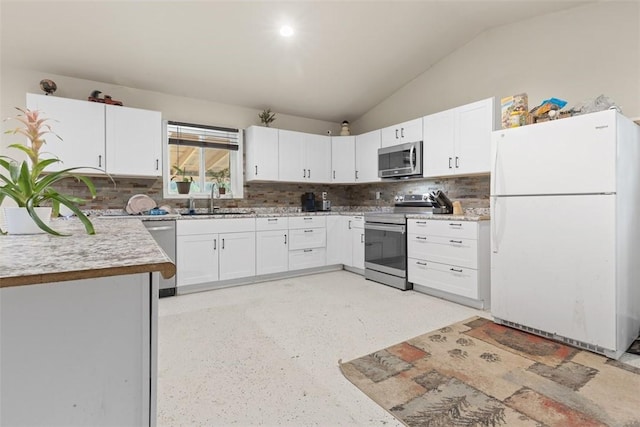 kitchen with a sink, stainless steel appliances, white cabinets, light countertops, and vaulted ceiling