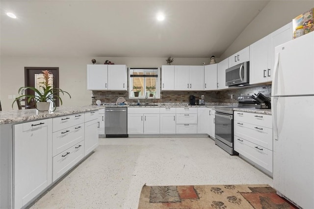 kitchen with lofted ceiling, decorative backsplash, appliances with stainless steel finishes, white cabinets, and a sink