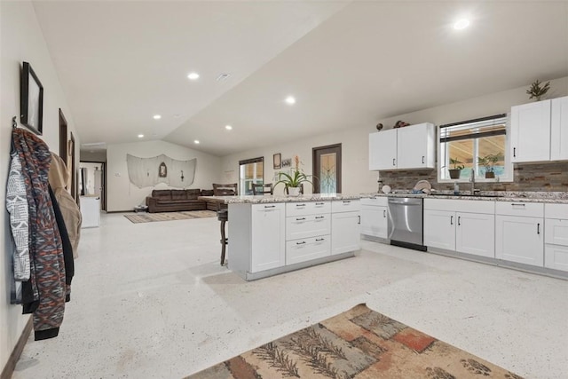 kitchen with open floor plan, dishwasher, a breakfast bar, lofted ceiling, and a sink