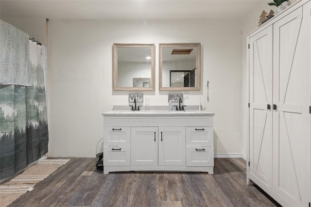 bathroom featuring curtained shower, double vanity, wood finished floors, and a sink