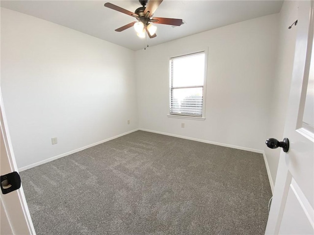 spare room with dark colored carpet, baseboards, and a ceiling fan