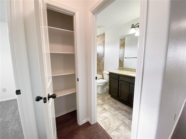 bathroom with tile patterned floors, a walk in closet, visible vents, toilet, and vanity