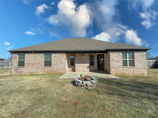 rear view of house with brick siding, a patio area, an outdoor fire pit, and a lawn