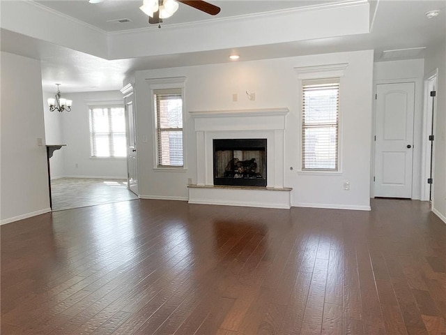 unfurnished living room with dark wood finished floors, ceiling fan with notable chandelier, a fireplace with raised hearth, and baseboards