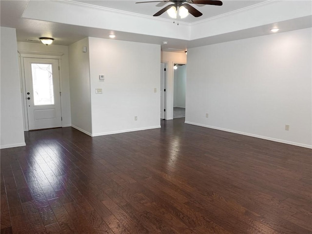 unfurnished room with ceiling fan, baseboards, a tray ceiling, ornamental molding, and dark wood-style floors