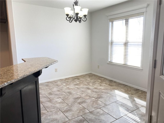 unfurnished dining area featuring light tile patterned floors, baseboards, and a chandelier