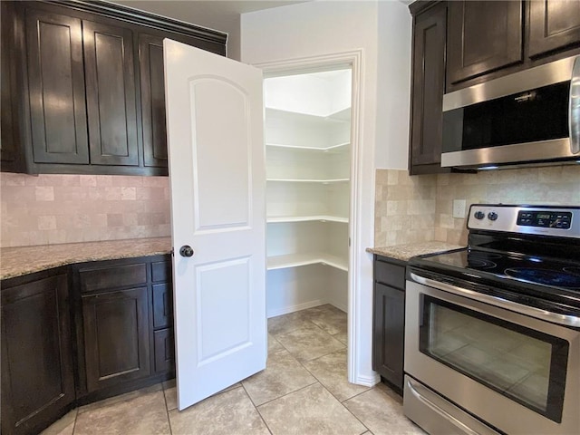 kitchen with dark brown cabinetry, backsplash, stainless steel appliances, and light stone counters