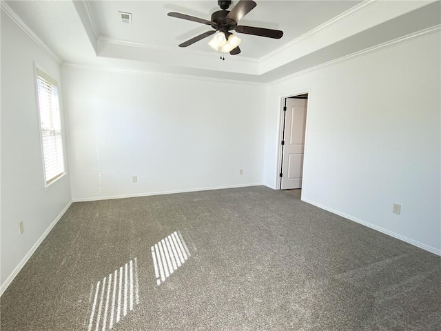 carpeted empty room featuring baseboards, a raised ceiling, and crown molding