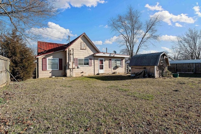 rear view of house with an outdoor structure, a yard, fence, and a shed