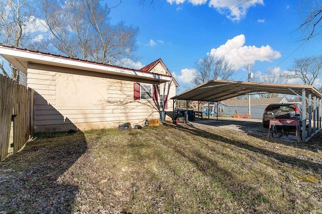 view of home's exterior with a lawn, a detached carport, driveway, and fence