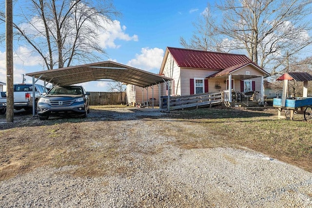 view of front of house with concrete block siding, driveway, covered porch, a carport, and metal roof