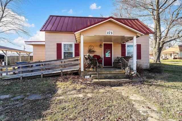 bungalow-style home with fence, covered porch, and metal roof