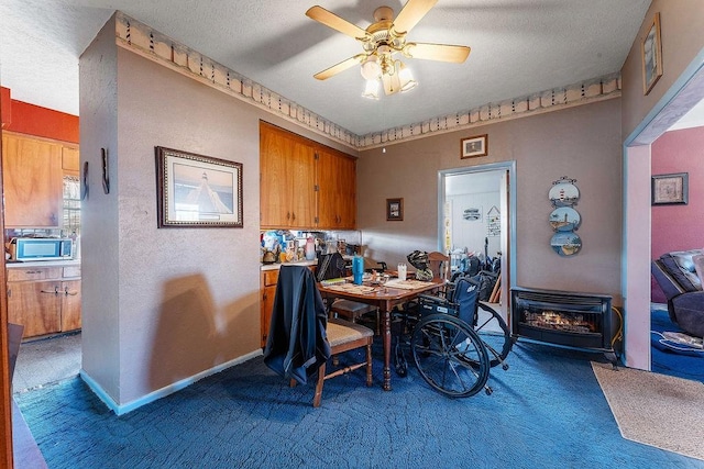 carpeted dining room with a ceiling fan, baseboards, a textured wall, and a textured ceiling