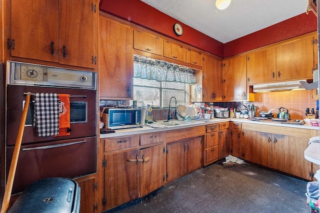 kitchen with under cabinet range hood, gas cooktop, tasteful backsplash, wall oven, and light countertops