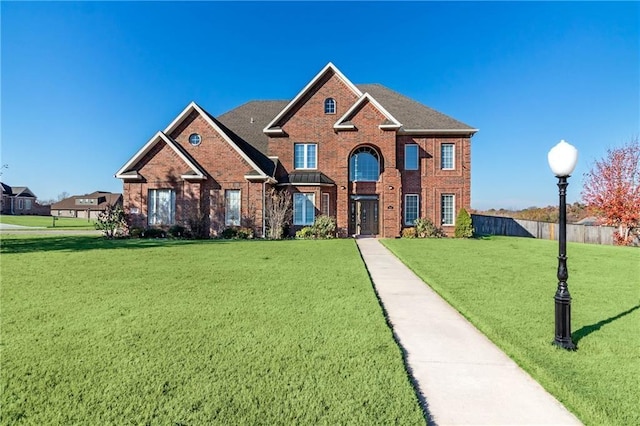 view of front of home featuring brick siding, a front lawn, and fence