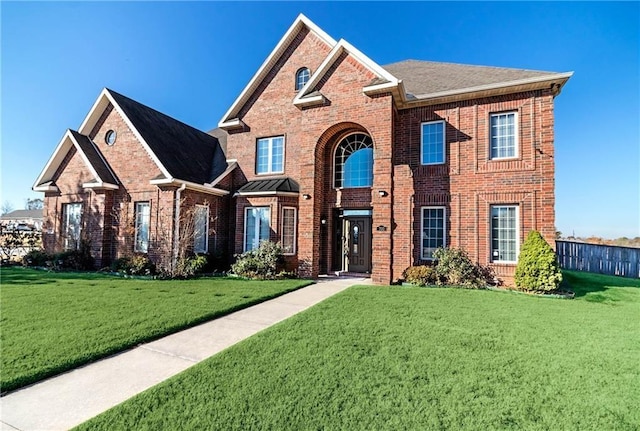 traditional-style home featuring brick siding, a front yard, and roof with shingles