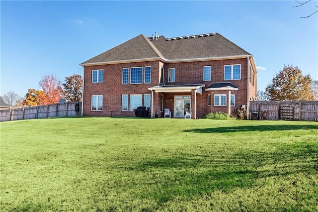 back of property featuring brick siding, a lawn, and a fenced backyard